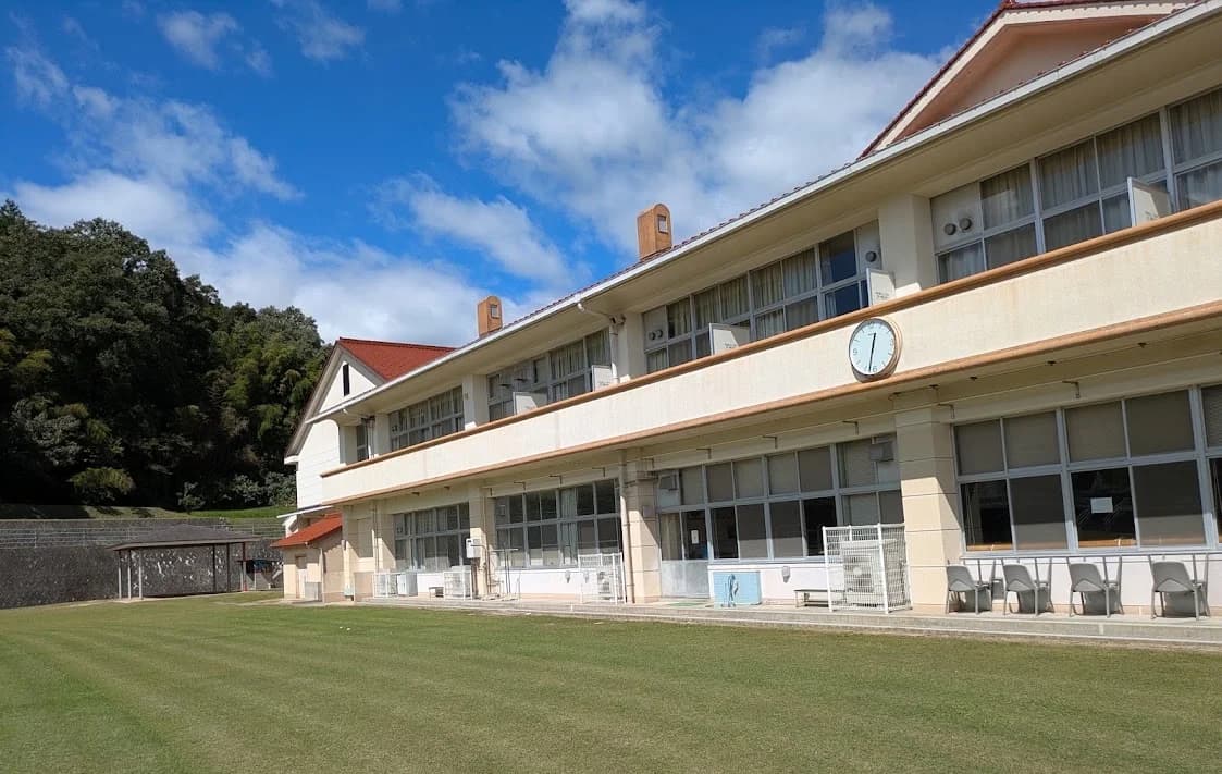 青空の下に建つ、会場となった旧小学校の校舎と芝生の校庭